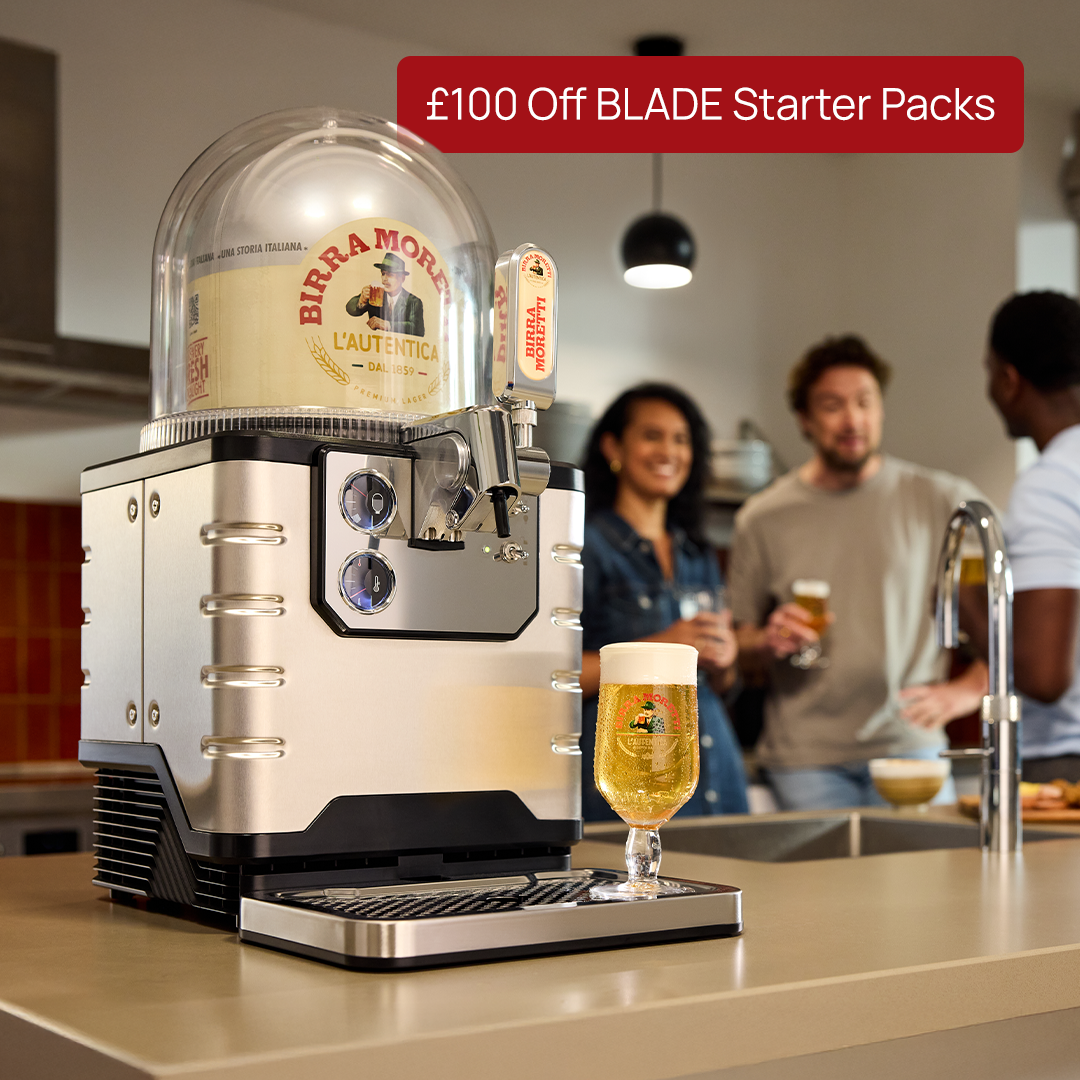 BLADE beer dispenser with glass of beer on a kitchen counter, people in the background.