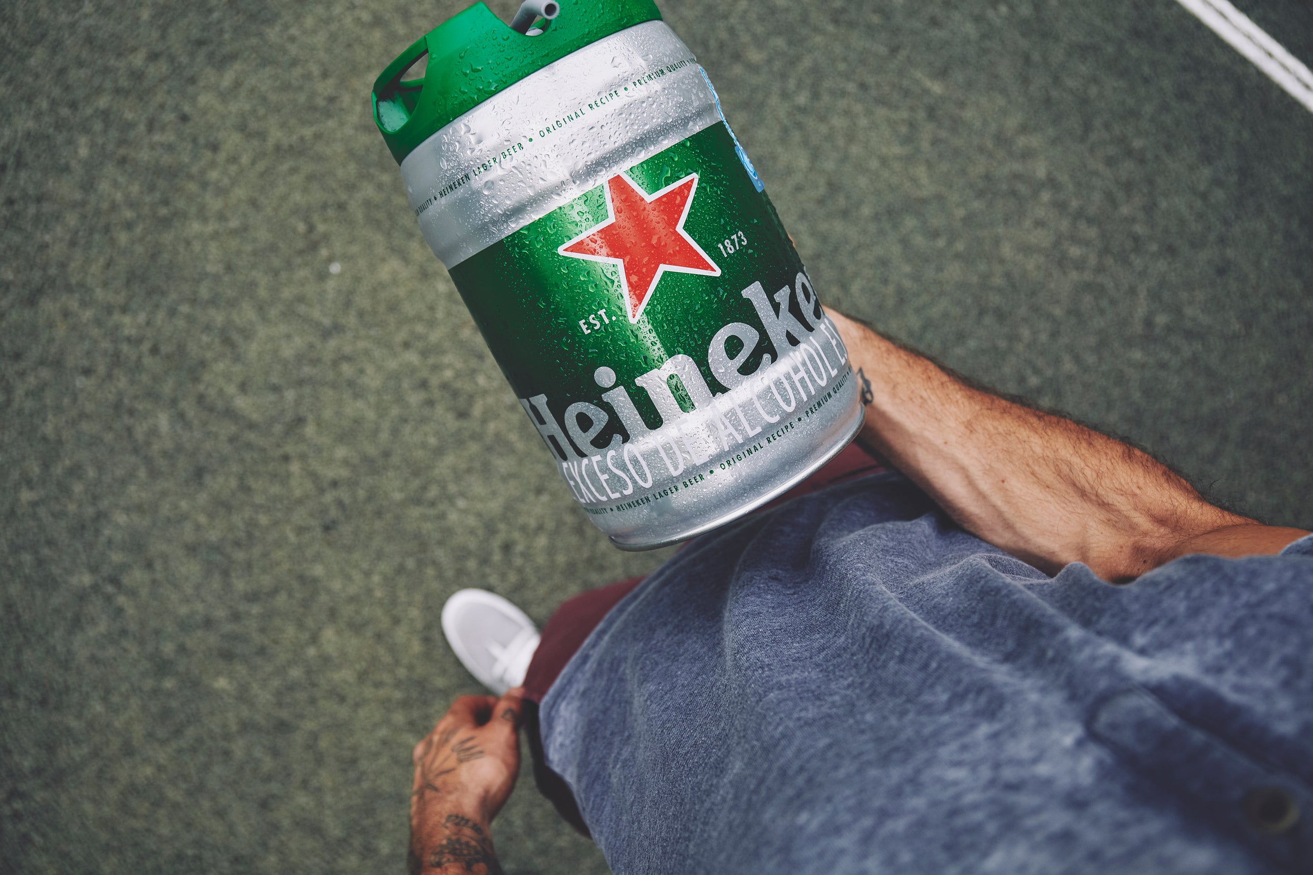 Person holding a Heineken 5L draught beer keg on a concrete surface.