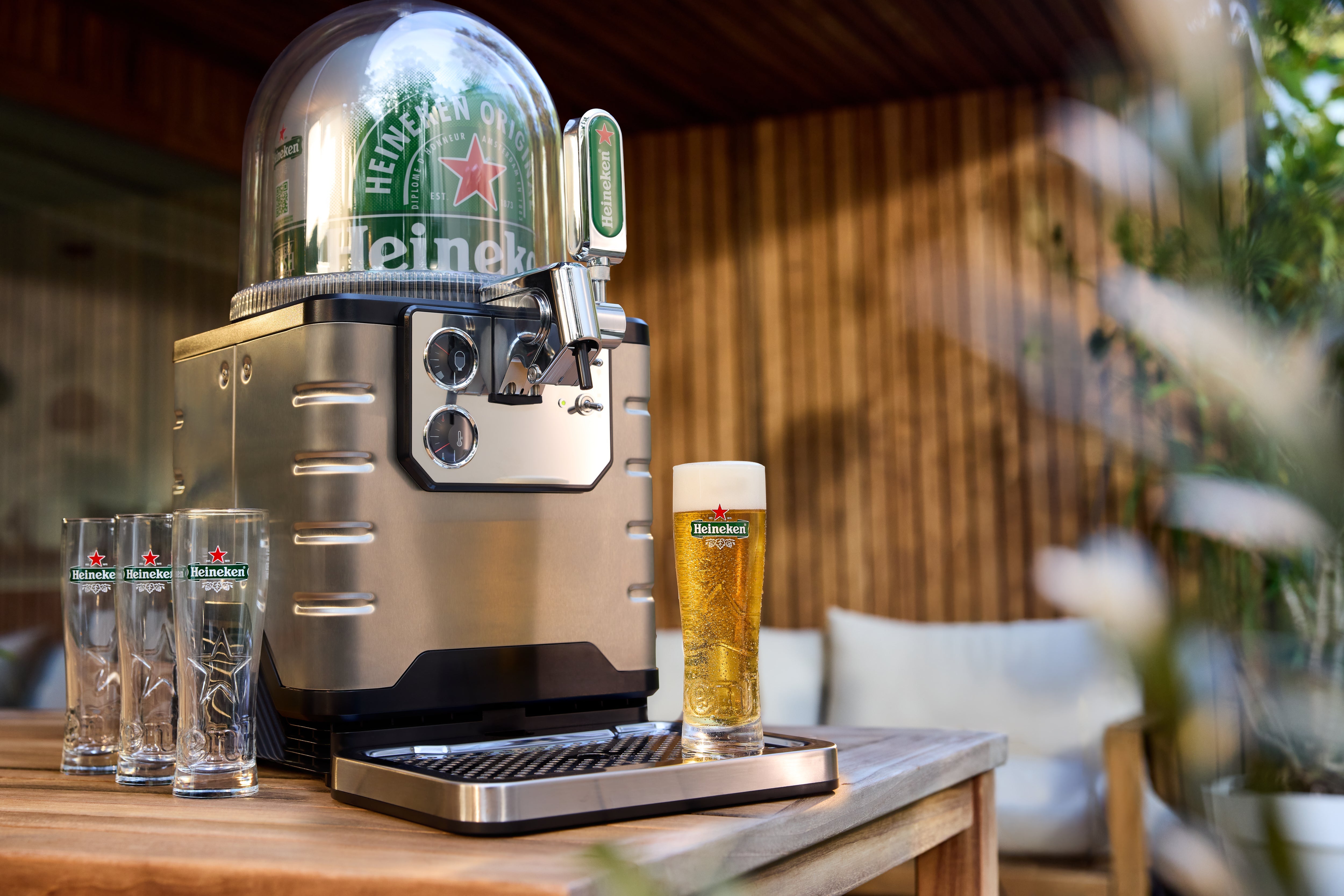 Heineken beer dispenser with glasses on a wooden table outdoors