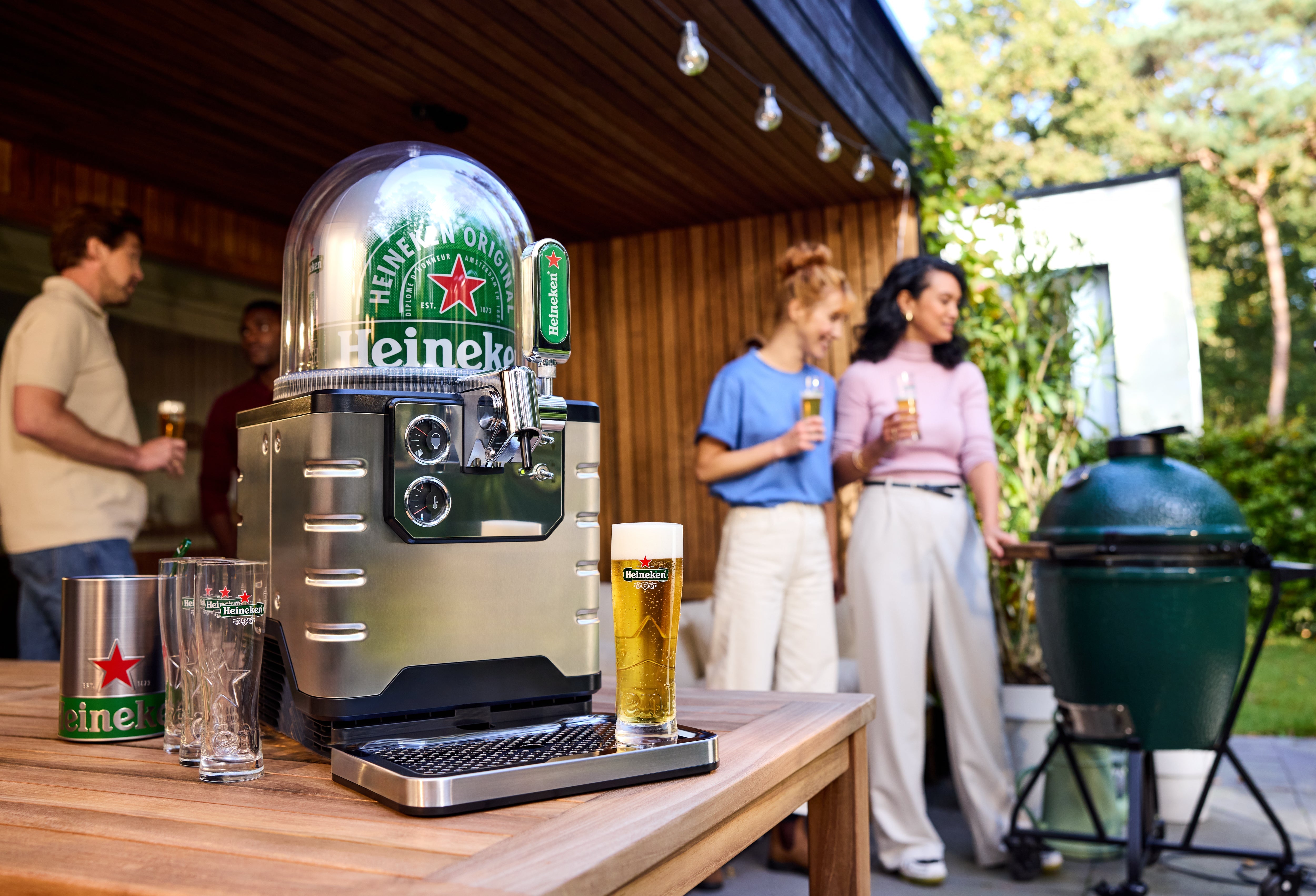 BLADE beer machine in a garden setting with people in the background enjoying a BBQ