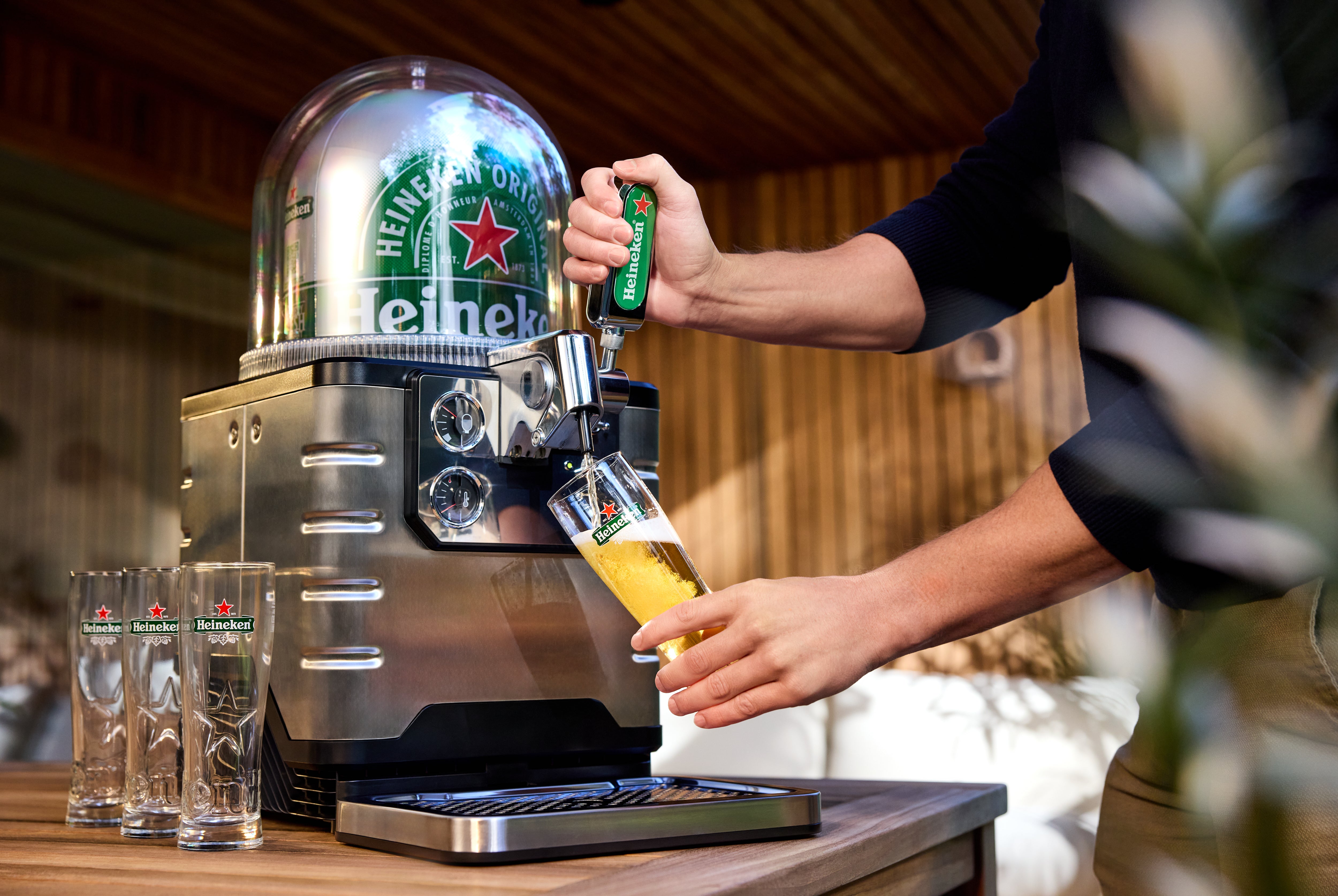 Heineken beer tap being used with glasses on a table.