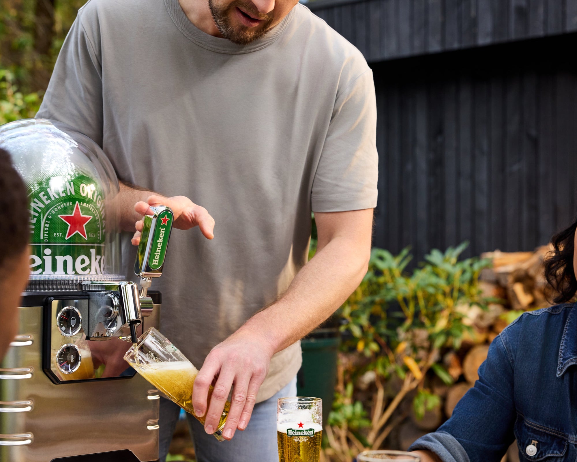 Man pouring Heineken beer from a BLADE beer tap at an outdoor table with a garden background