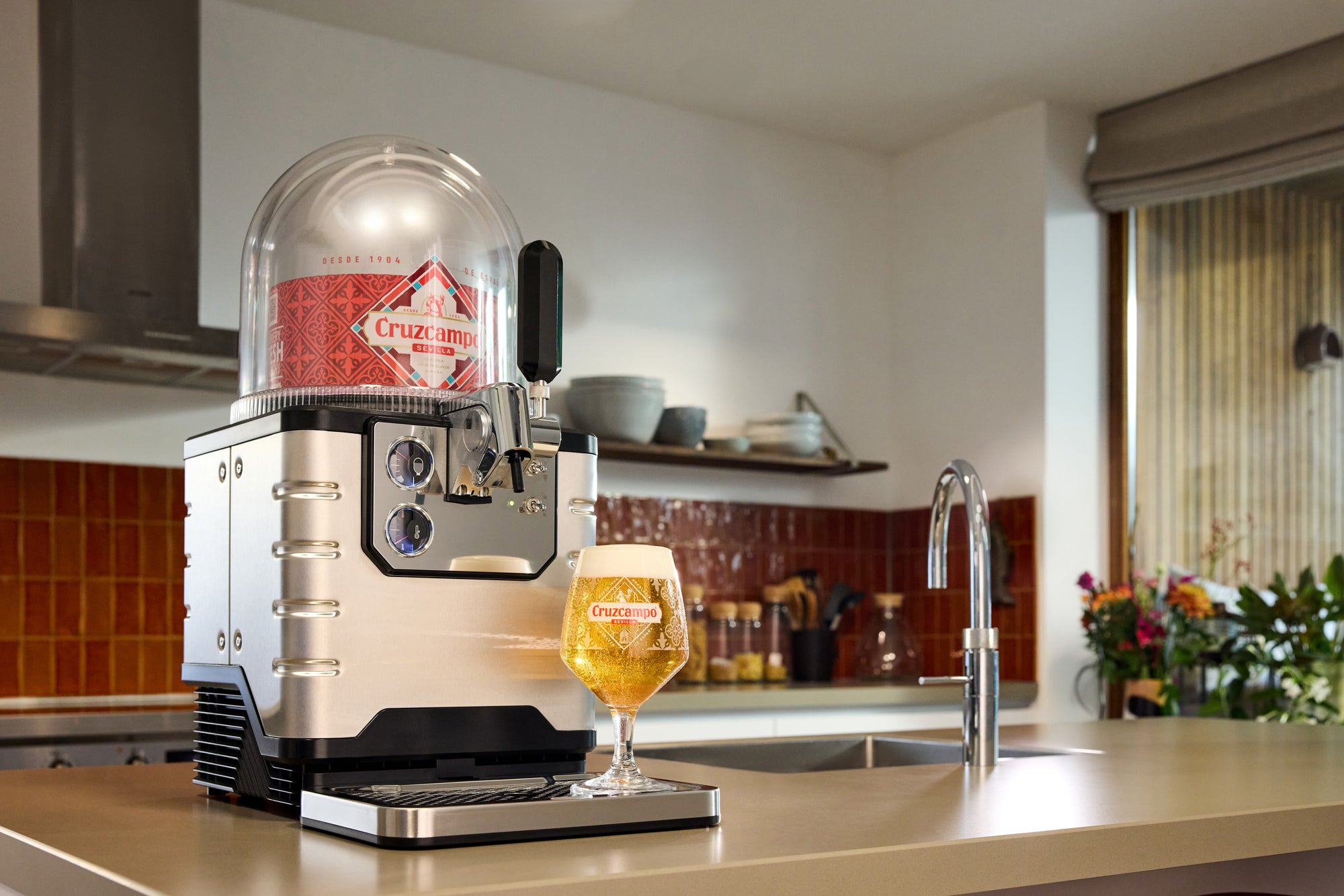 A BLADE beer tap on a kitchen counter with a glass of beer next to it.