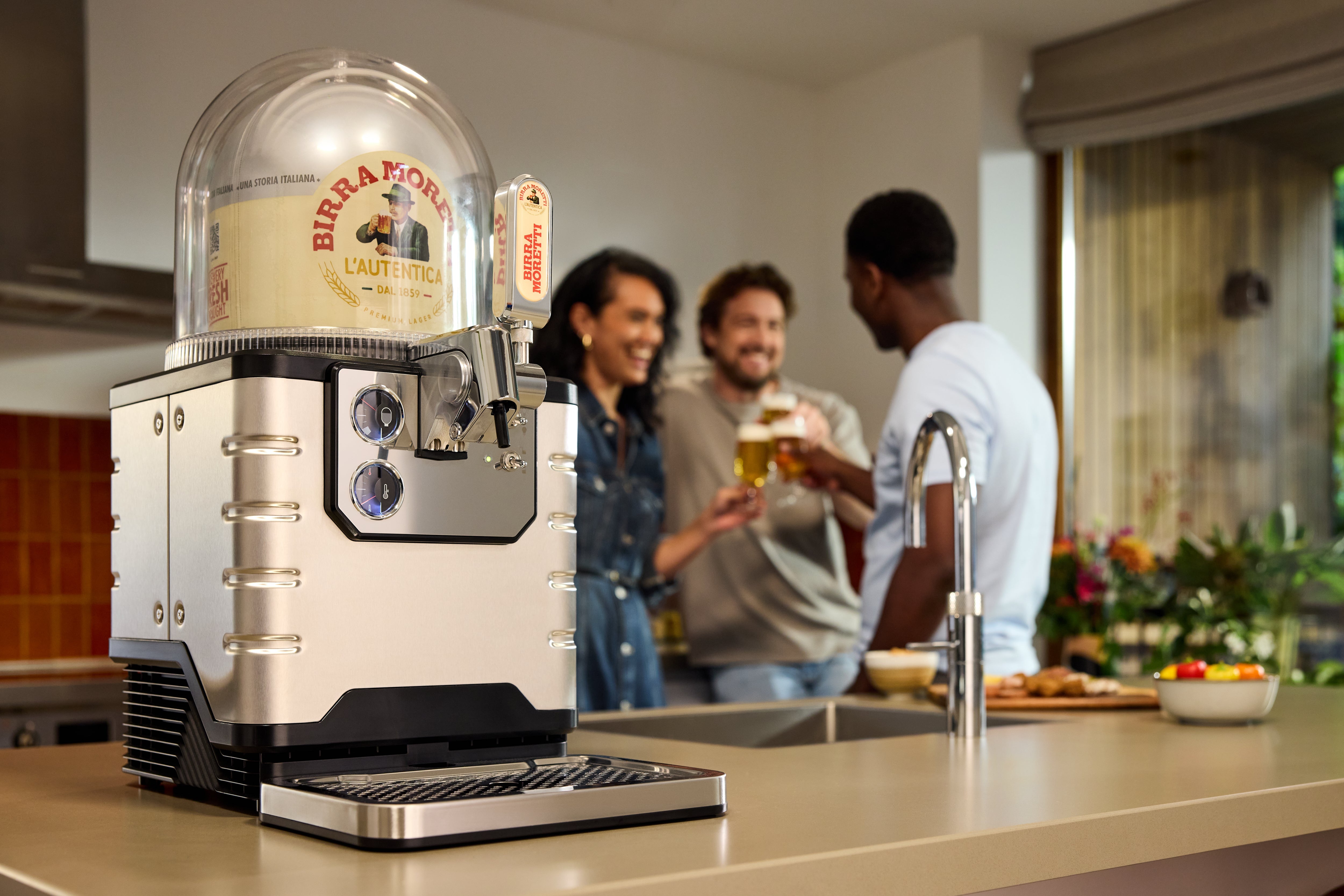 A BLADE beer machine on a kitchen counter with people in the background.
