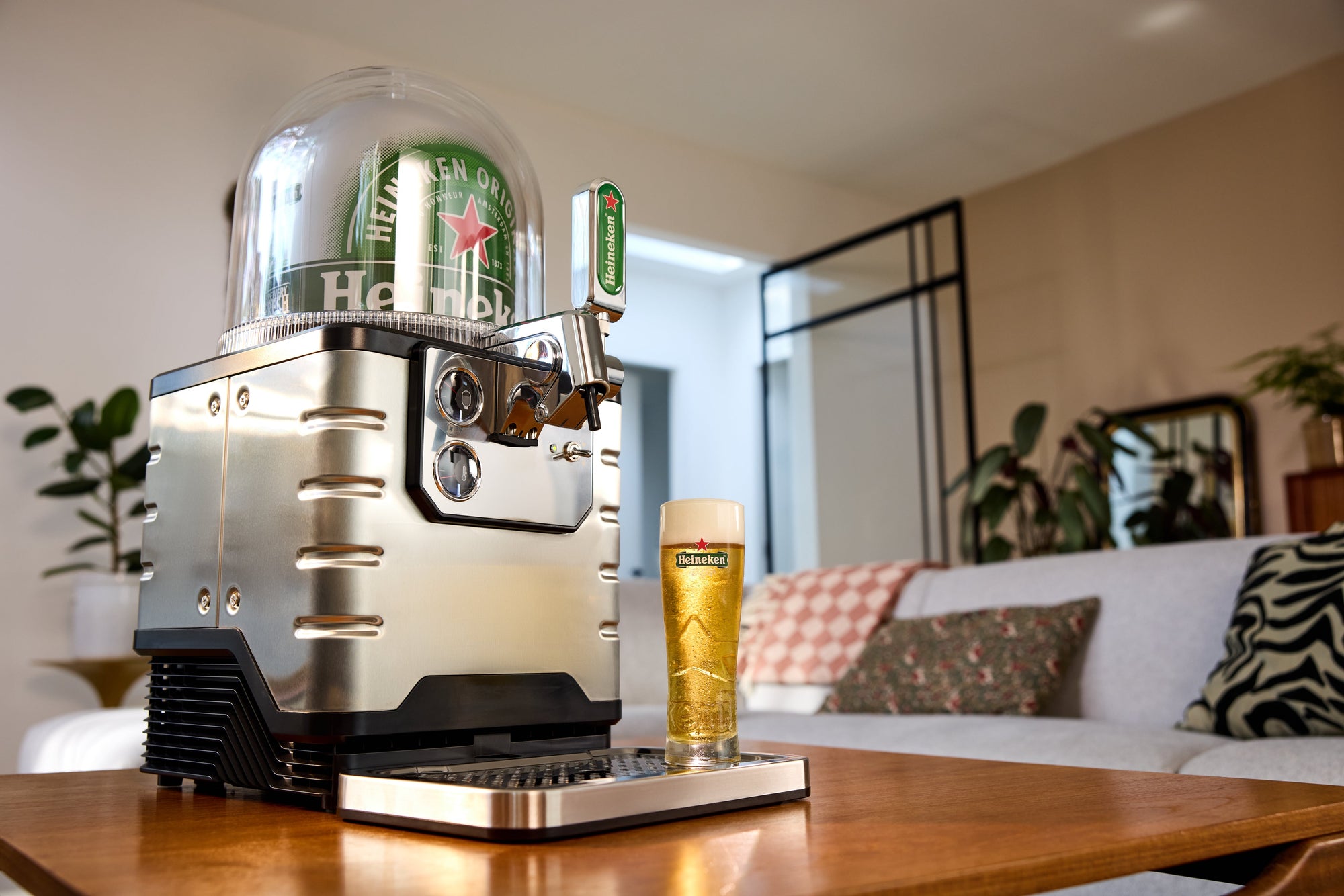 A BLADE home beer tap system on a table with a glass of beer in a living room setting.