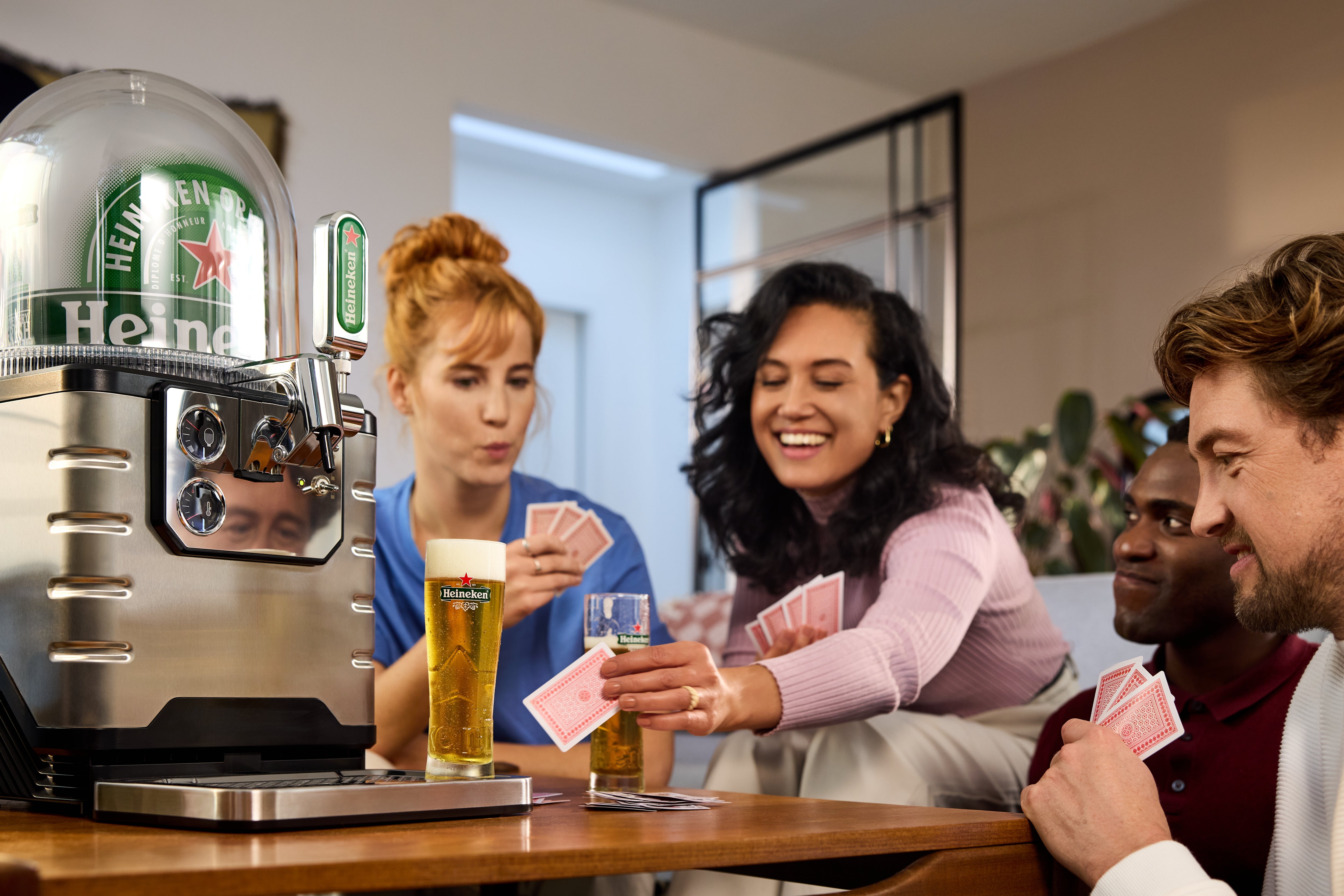 People playing cards around a table with a BLADE beer machine next to them