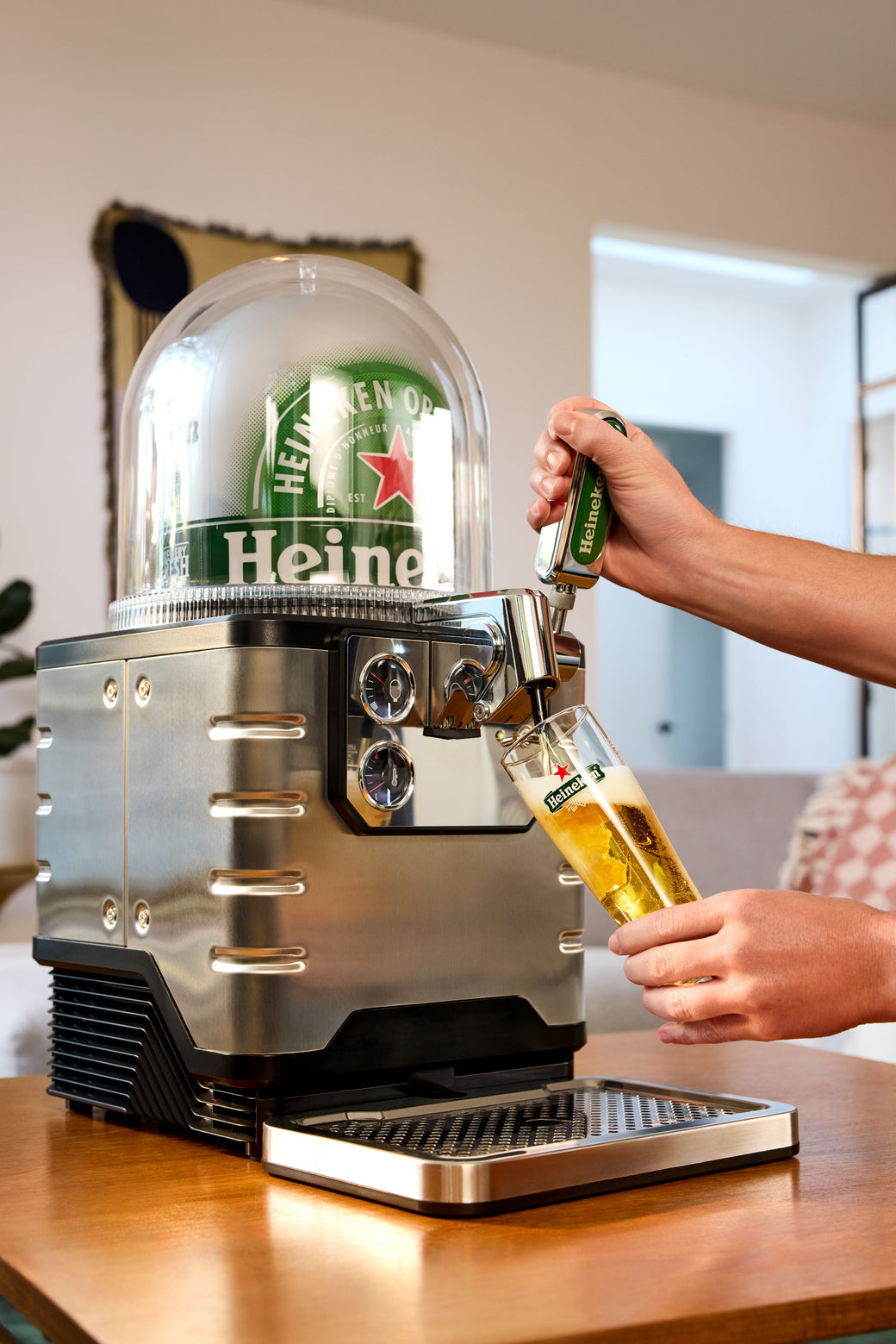 A person pouring a Heineken beer from a BLADE beer machine in a living room setting.
