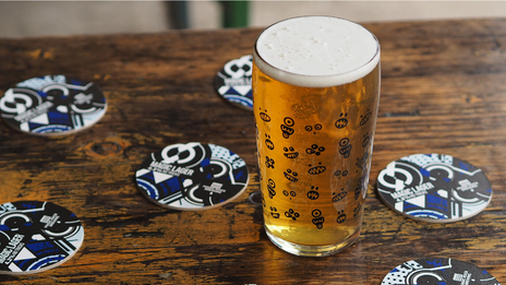 A pint of Magic Rock beer with a bunch of Magic Lager beer mats around it.