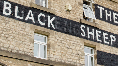 A building with the words, 'The Black Sheep' written on its bricks.