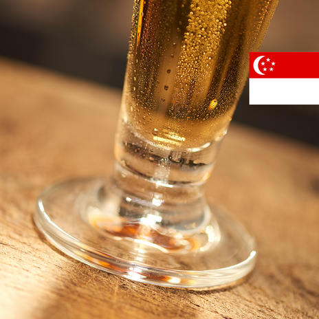 The bottom part of a glass of beer with the flag of Singapore in the top right corner.