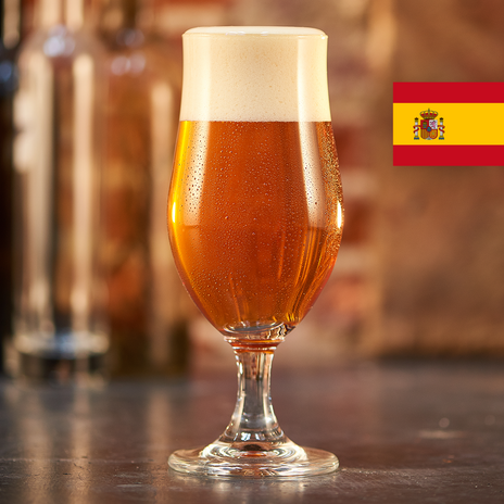 A full glass of golden brown beer with the flag of Spain in the top right corner.