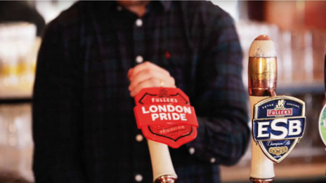 A man pulling a pint from a Fuller's London Pride beer tap.