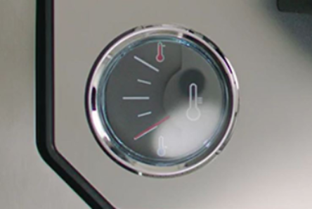 A person checks the temperature gauge on a beer dispenser to ensure the beer has reached the optimal temperature before pouring.