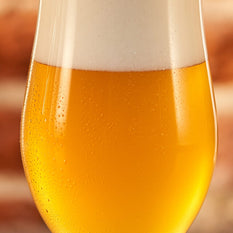 A full glass of fresh beer with small water drops on the side of the glass.