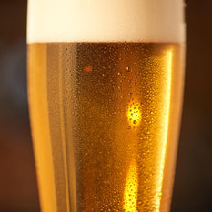 Close up of a beer glass with fresh lager beer and foam