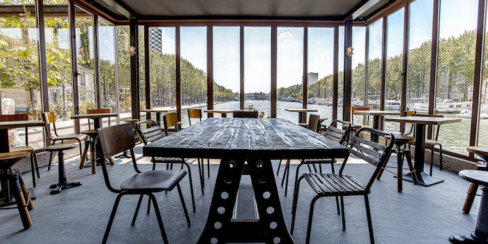 The interior of Paname Brewing Company in Paris, featuring a view of the river and comfortable seating.