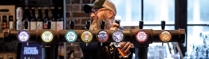 An employee at the Paname Brewing Company using one of the many beer taps to pour a beer.